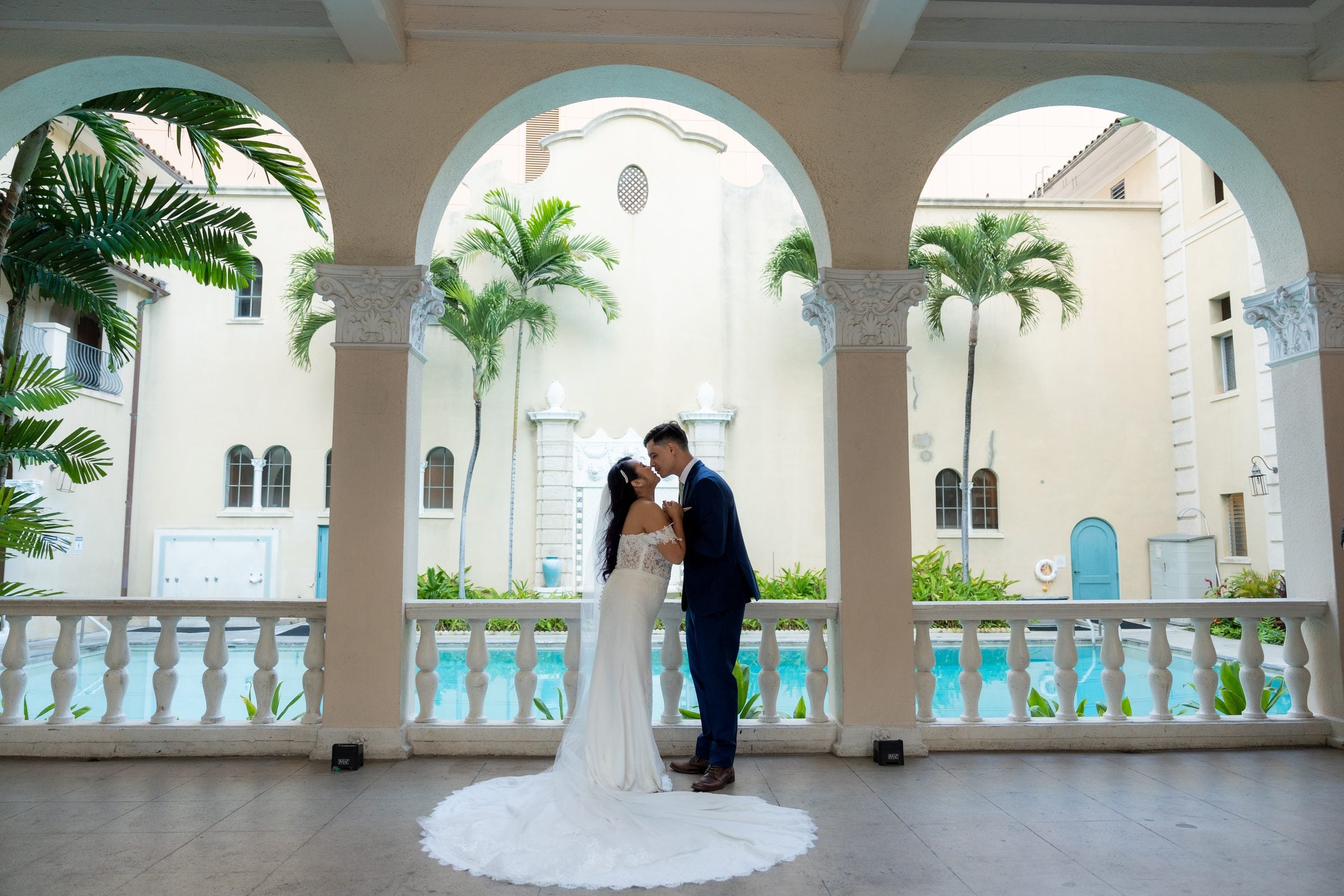 Adrianne and Ross kiss between the arches beside the pool.