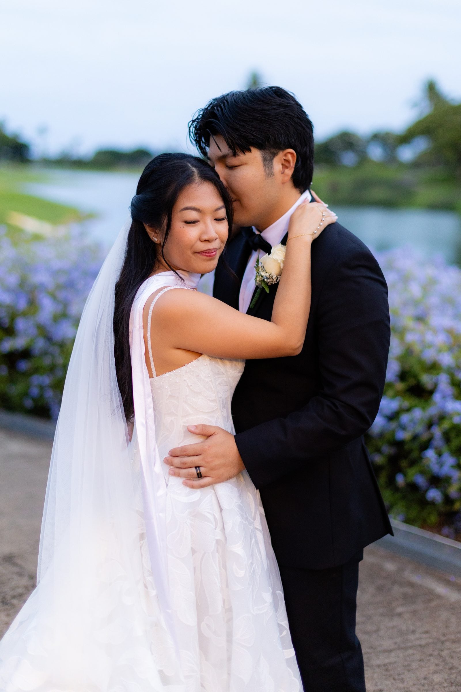 Brennan kisses Mia's forehead in the evening light by the water.