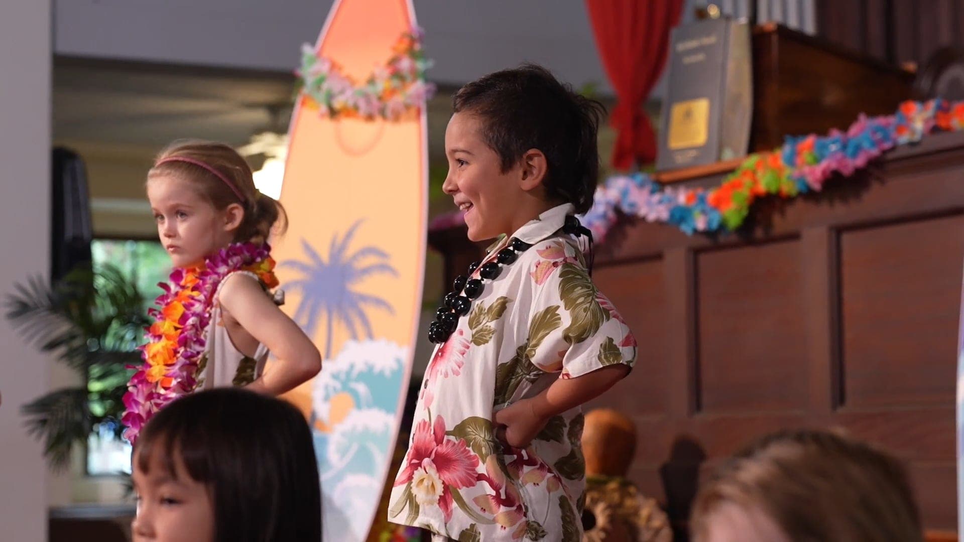 Children in lei and aloha wear on stage at a May Day celebration, a still from his event film.