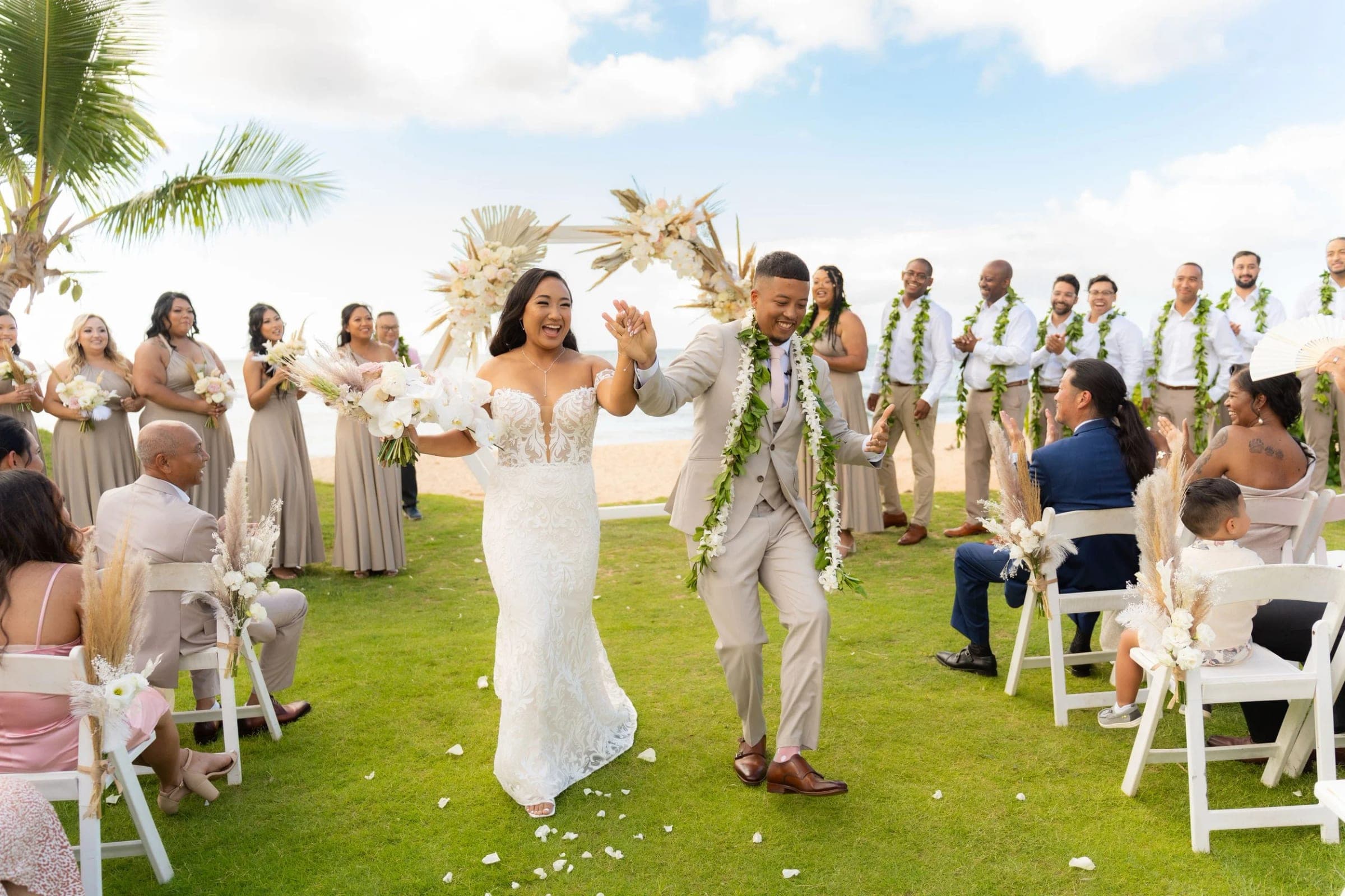 The couple walks back up the aisle on the lawn as their guests stand and cheer.
